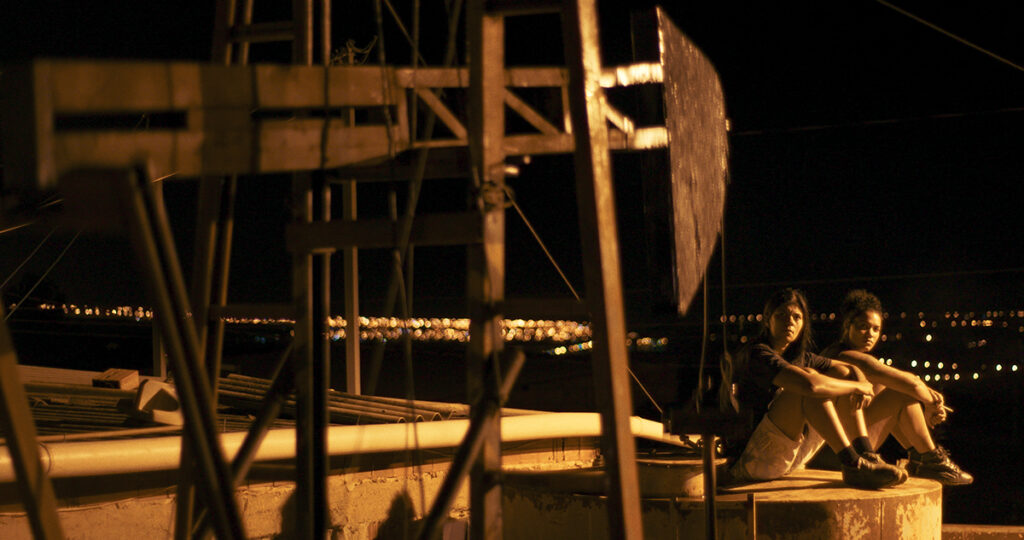 Still from "Dry Ground Burning" Women sit on a roof top. Image courtesy of Grasshopper Film